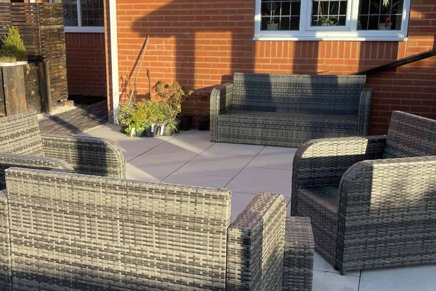 Grey rattan furniture creates enclosed seating area, on top of Florence Grey Porcelain Paving. Built by SP Landscapes.