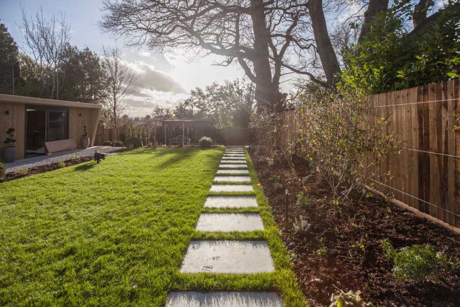 Path of Florence Grey Porcelain outdoor tiles laid in lawn along border running down length of garden. Design by Simon Orchard.