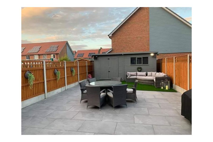 Fenced garden fully paved in Florence Storm Porcelain outdoor tiles UK, with shed at end and 2 sets of dining and lounge furniture.
