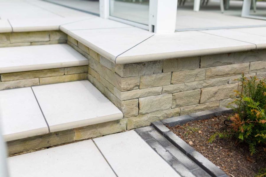 Florence White porcelain steps create edge of raised patio with glass railings reached by 2 matching steps.