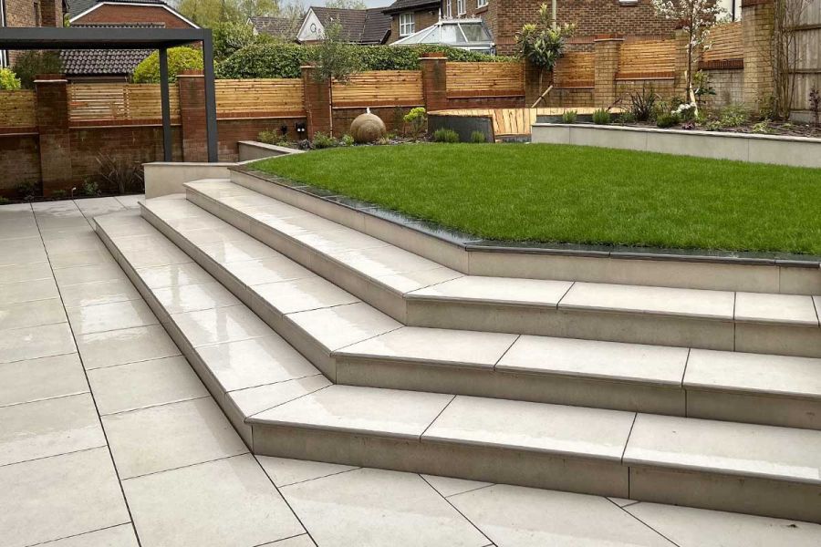 3 Florence White porcelain steps with bullnose edge profile rise to trapezium-shaped lawn with raised planted border at back.