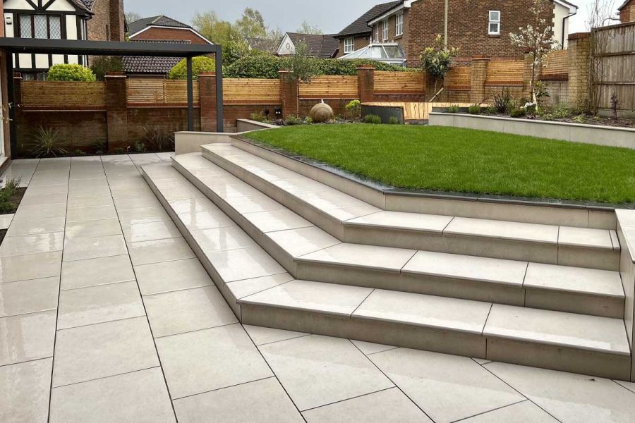 Florence White Porcelain patio with large impressive steps leading up towards a raised lawn and flower beds.