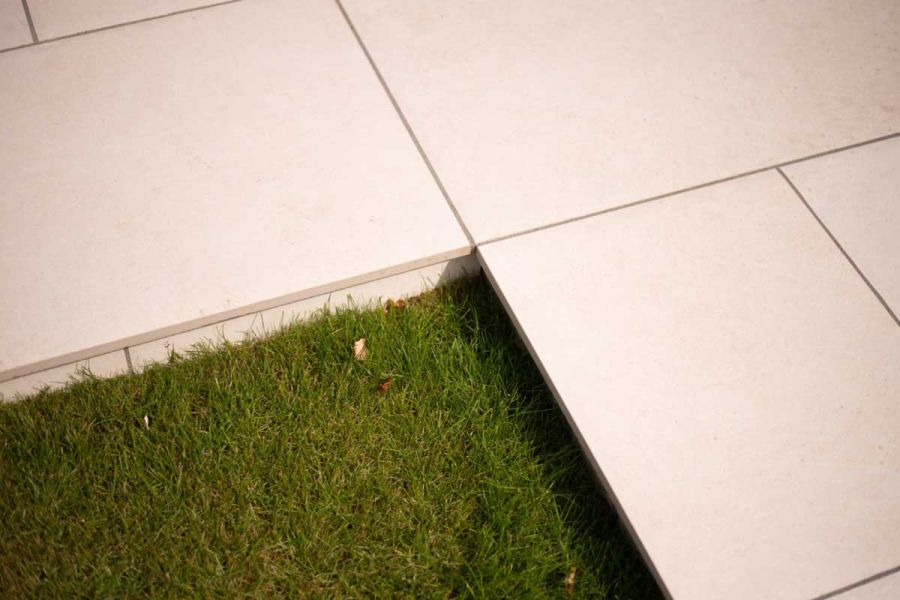 Florence white outdoor Porcelain tiles raised slightly above a luxurious grass lawn.