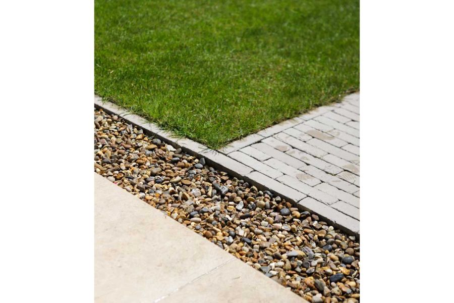 Gravel strip separates paving from Stone Grey clay pavers next to lawn edged with matching bricks. Design by Garden Tamer.