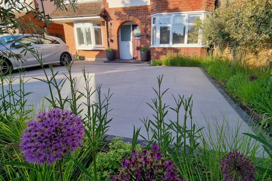 Fish lens type view of Kandla Grey Porcelain Paving Garden Tiles UK used on large driveway surrounded by planting.