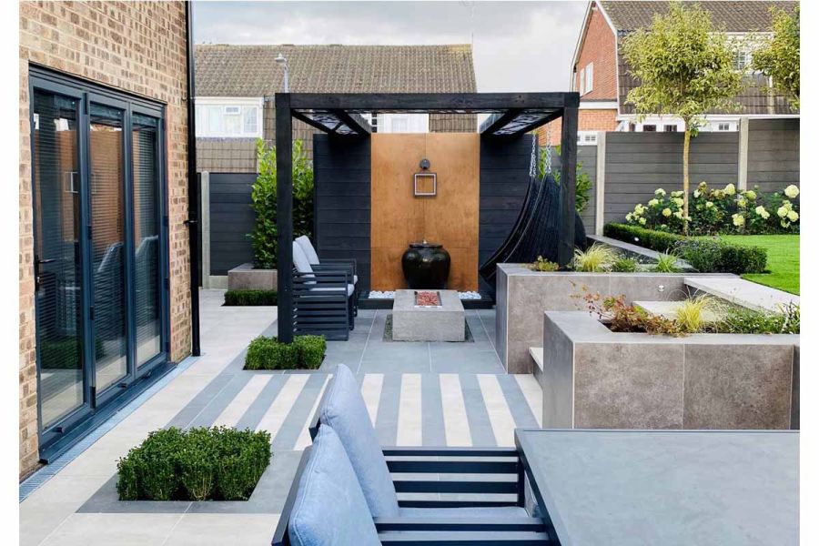 Cream and steel grey porcelain planks used leading to steps, pergola in the background with firepit and seating area.