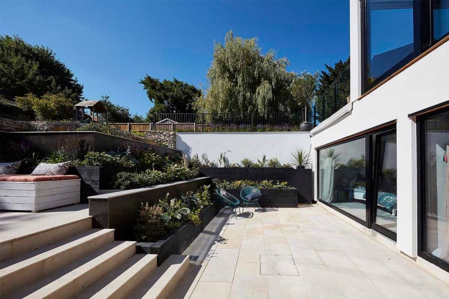Contemporary house with bi-fold doors leading to area paved with Gea Porcelain Paving and DesignClad exterior cladding.