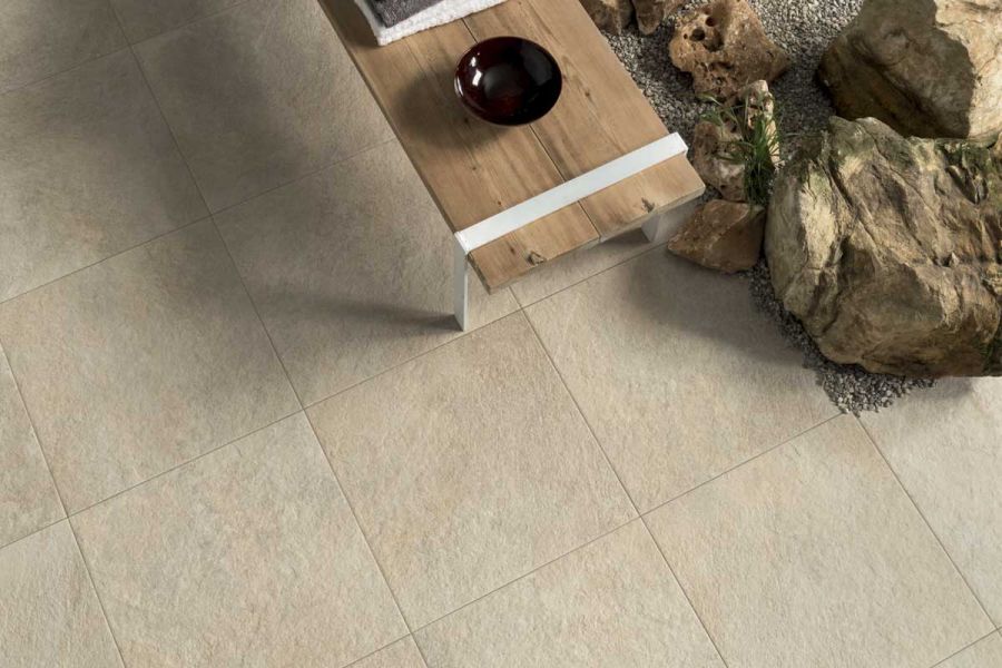 Close-up of patio area with Gea Porcelain outdoor tiles from London Stone, featuring a small, wooden coffee table on the side.