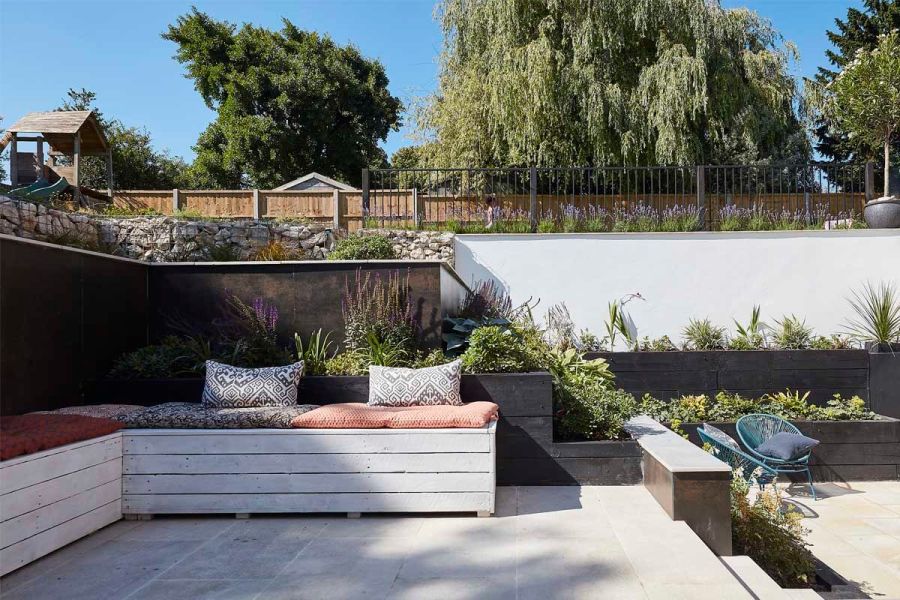 Inspirational garden transformation featuring Gea Porcelain Paving and a cosy seating area cladded with DesignClad Steel Dark.