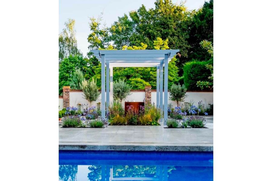 Wooden garden pergola dominating this modern garden that features a swimming pool with Gea porcelain coping stones and paving.