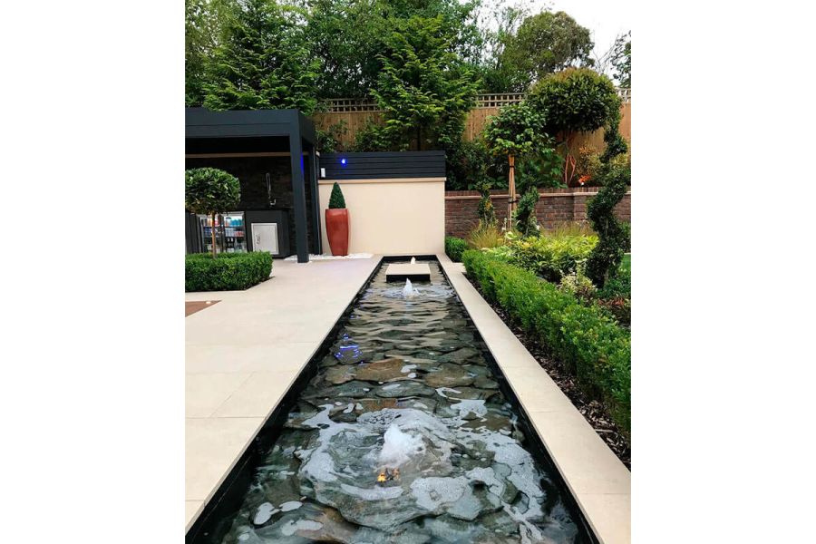 Formal rectangular pool with babbling water features, set in Golden Stone Porcelain paving with matching wall at far end.