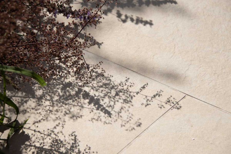 The texture of Golden Stone Porcelain Paving contrasting against the shadow from over hanging foliage.