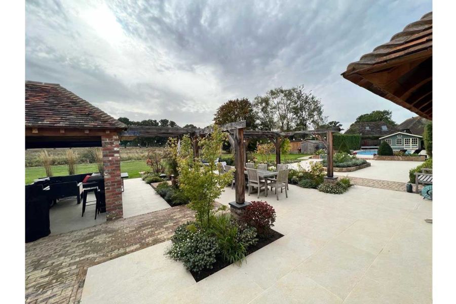 Golden Stone Porcelain Paving used in large garden with both brick and wooden pergolas, an outhouse and swimming pool.