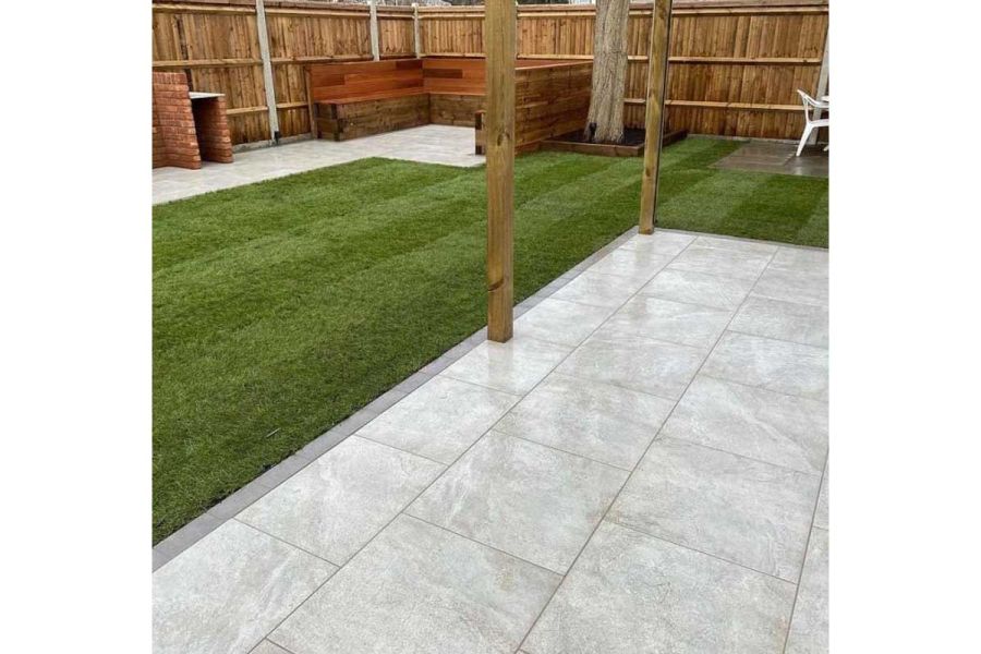 2 wooden posts rise from rectangular paved area edged with steel grey porcelain setts, next to lawn. Built by GRC Landscapes.