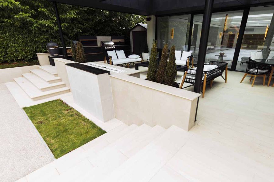 2 sets of white steps descend from covered patio on either side of wall faced with Off White Designclad exterior cladding.