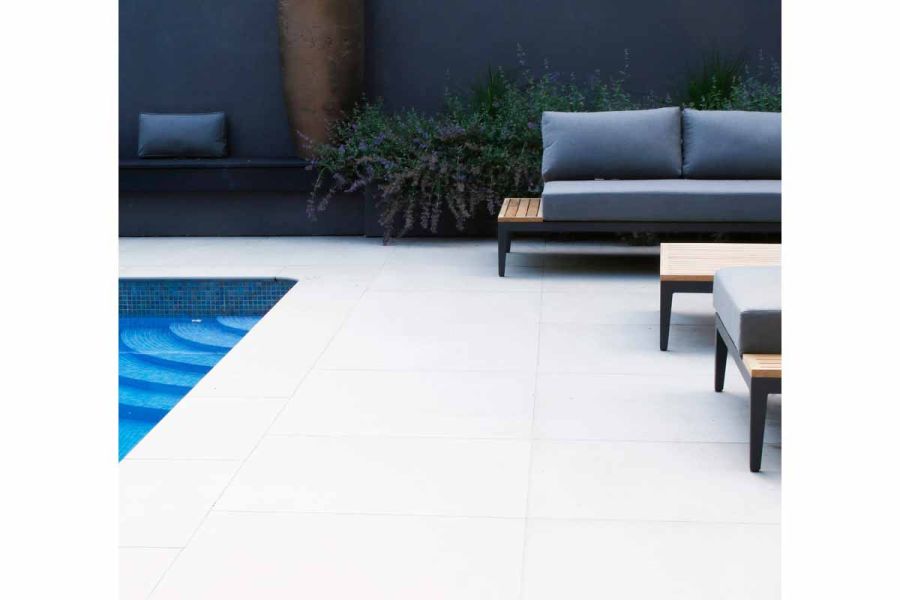 Design by Greencube. Poolside view of Yard 1200x1200 Porcelain Paving, with green and purple plants in the background.