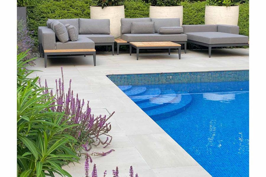 View poolside shows yard 1200x1200 large patio slabs used as patio and pool copings. Designed by Greencube.