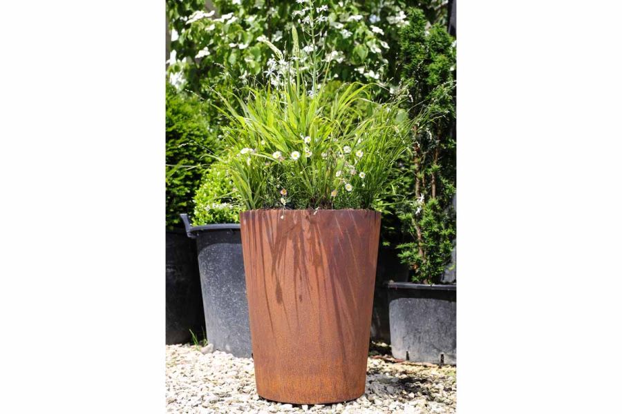 Metal tapered cylinder filled with lush green planting by Form Plants which contrasts with orange-brown of Corten steel.