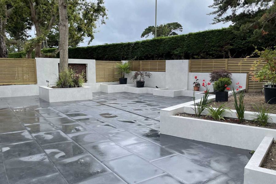 Large fully paved garden with rectilinear raised beds faced with Hydra Argen DesignClad cream porcelain cladding.