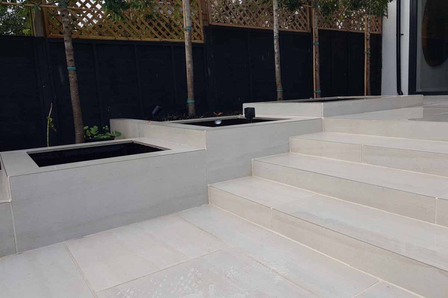 Faro porcelain paving used as steps descend from large patio area, built in large planters surround. Built by John Gale.