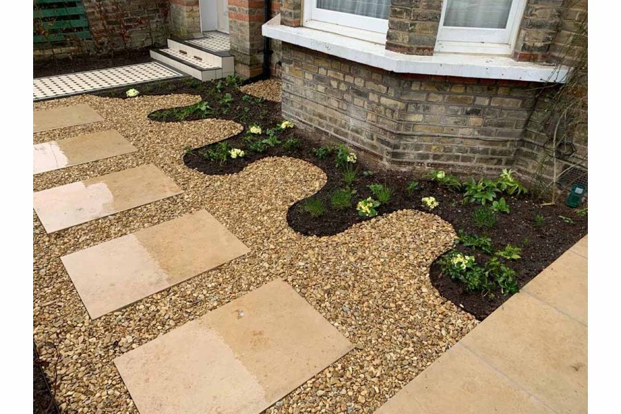 Front garden of period house with curvy flower bed under bay window and gravel with Jura Beige 900x600 sawn paving slabs.