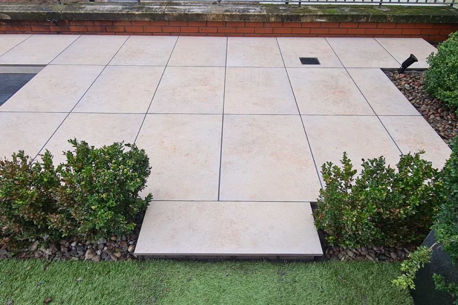 Jura Beige Limestone laid in a distinctive rectangular grid pattern surrounded by box hedging in beds topped with river washed pebbles.