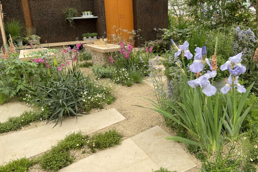 Jura Beige Smooth Limestone bespoke slabs with hoggin, planted with flowering irises and foxgloves with brick-plinthed tables.