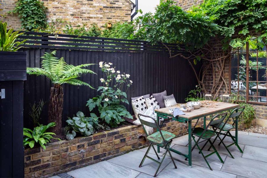 Courtyard by Sarah Kay Garden Design with Kandla Grey sandstone paving. Chairs, table and plants reflected in mirror against fence.