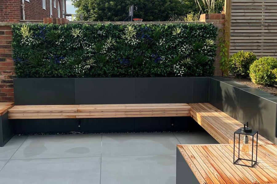 Cantilevered wooden benches attached to raised beds border area paved with Yard large format porcelain tiles. Built by Kent Best.