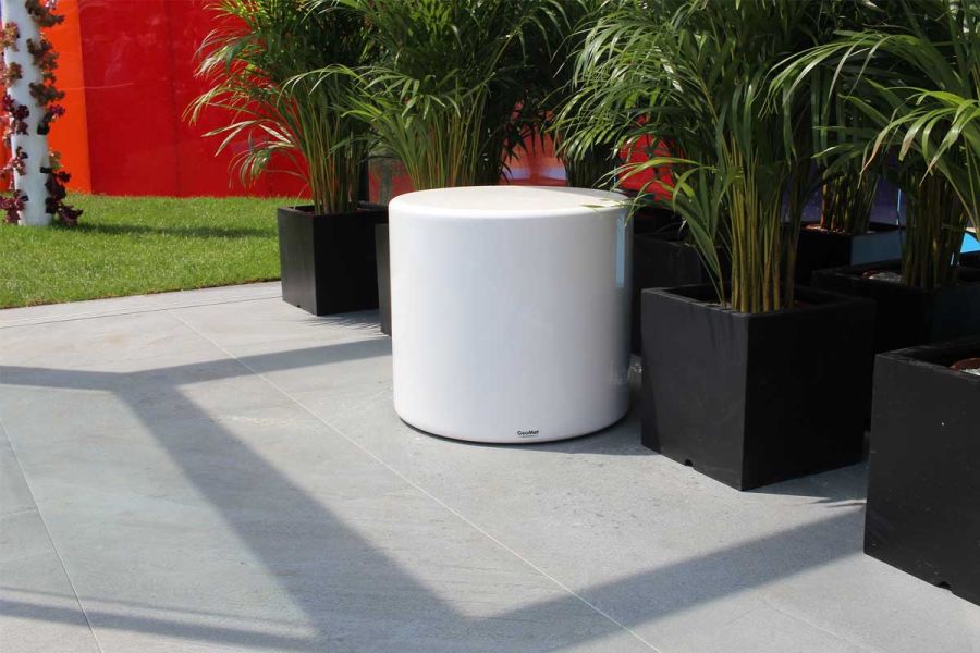 Kirkby Porcelain plank paving edges 1200 x 600mm patio tiles jointed with pale grout, with square black planters and white stool.