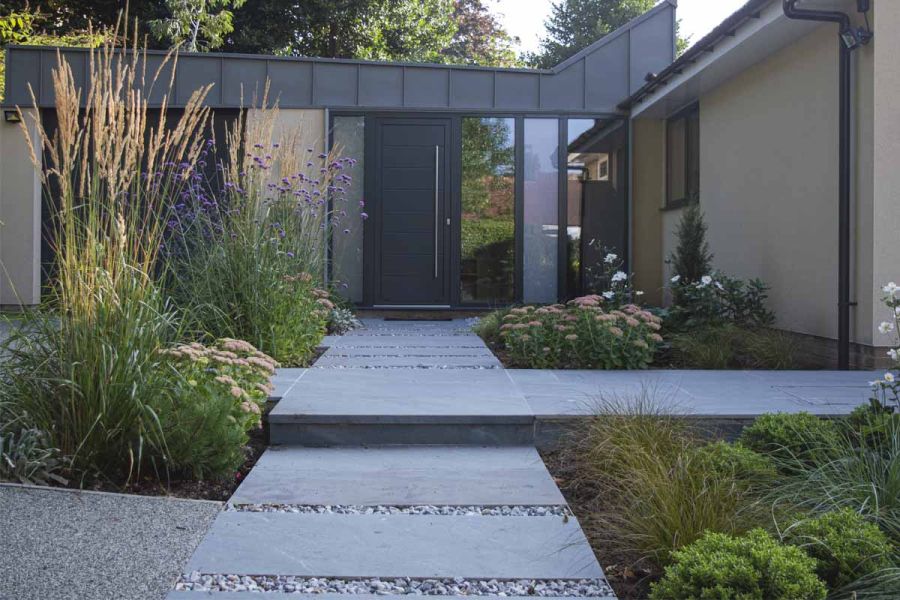 Kirkby Porcelain slabs set in gravel lead to modern one-storey home, with raised jointed paving path set at right angle.