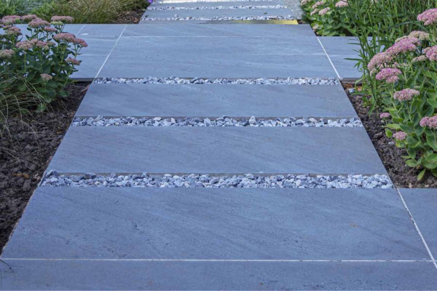 Path of Kirkby vitrified porcelain patio slabs between beds of sedum, laid with gravel insets or jointed with pale grout.