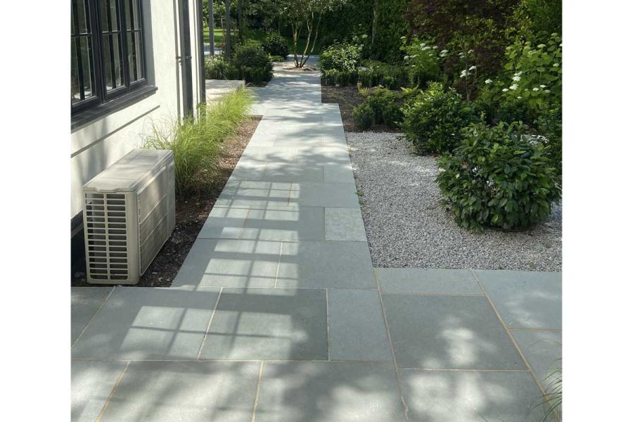 Light reflects from windows on Kota Blue Limestone Paving running between house and gravel bed. Design by Thouvenin Landscapes.