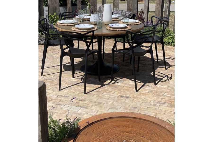 Outdoor dining set on London mixture clay paver patio with corten steel raised pond. Design by Alan Williams. Built by Landform.