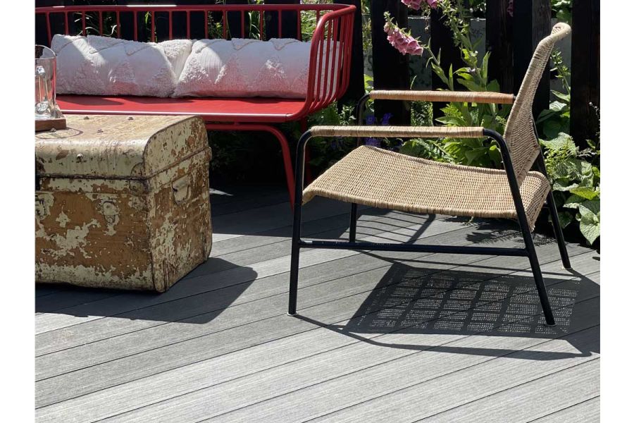 Rattan armchair with metal trunk as coffee table sit on DesignBoard Charcoal composite decking. Design by Alan Williams.