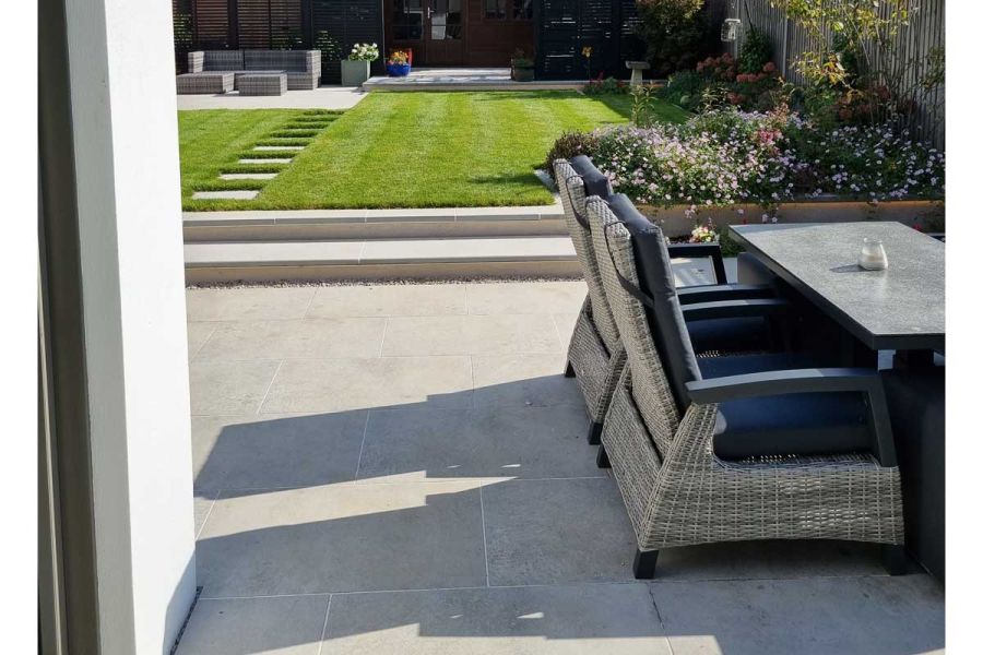Ground level Light Grey Porcelain patio stepping up onto a raised lawn that leads onto an upper hard landscaped terrace.