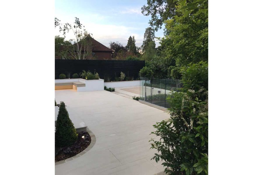 Large area in Faro Porcelain Paving, with raised border and well spaced geometrically shaped beds, By Landscape Design Studio.