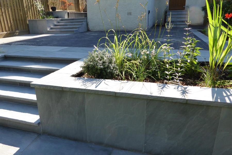 Planted raised bed topped with Kandla Grey Indian sandstone coping stones, faced with matching paving, designed by Landspace.