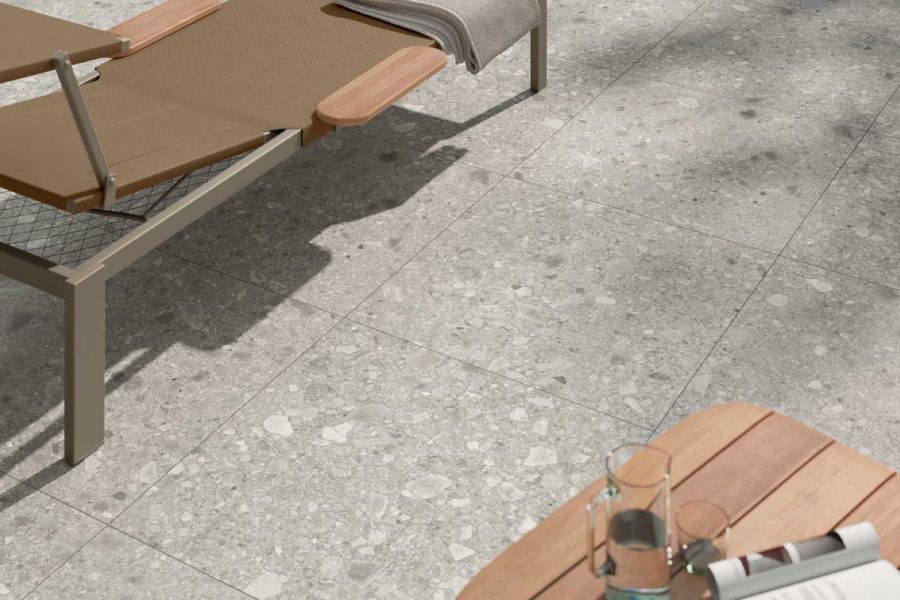 Lounger and wooden table sit on Brera 800x800 porcelain paving, laid stack bond, with natural pattern clearly visible.
