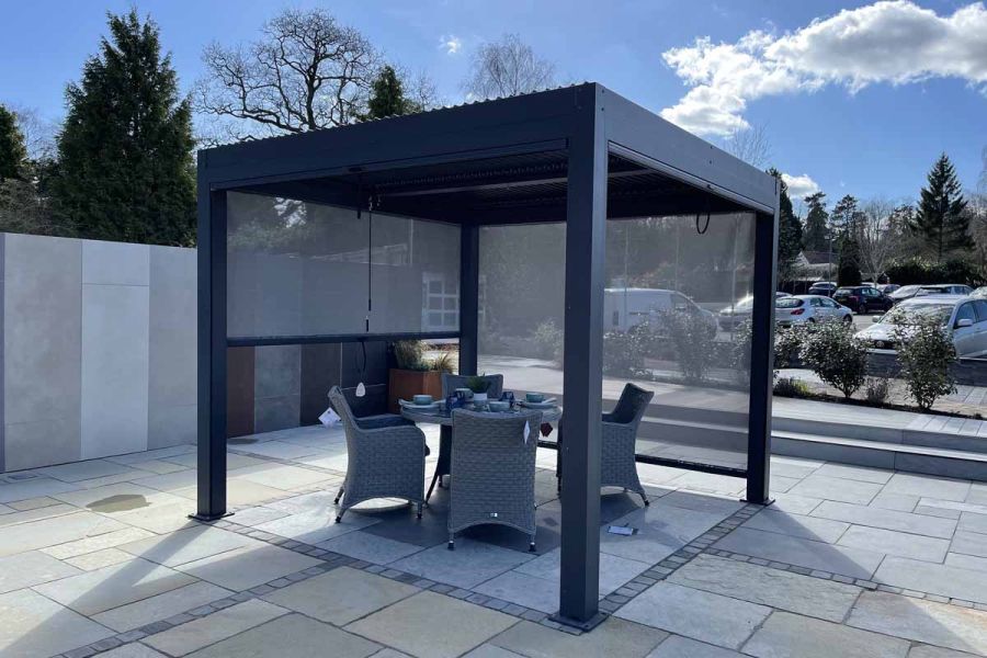 LeisureGrow Dark Grey Metal Gazebo with 2 blinds partially and fully lowered, on natural stone paving at London Stone showroom.