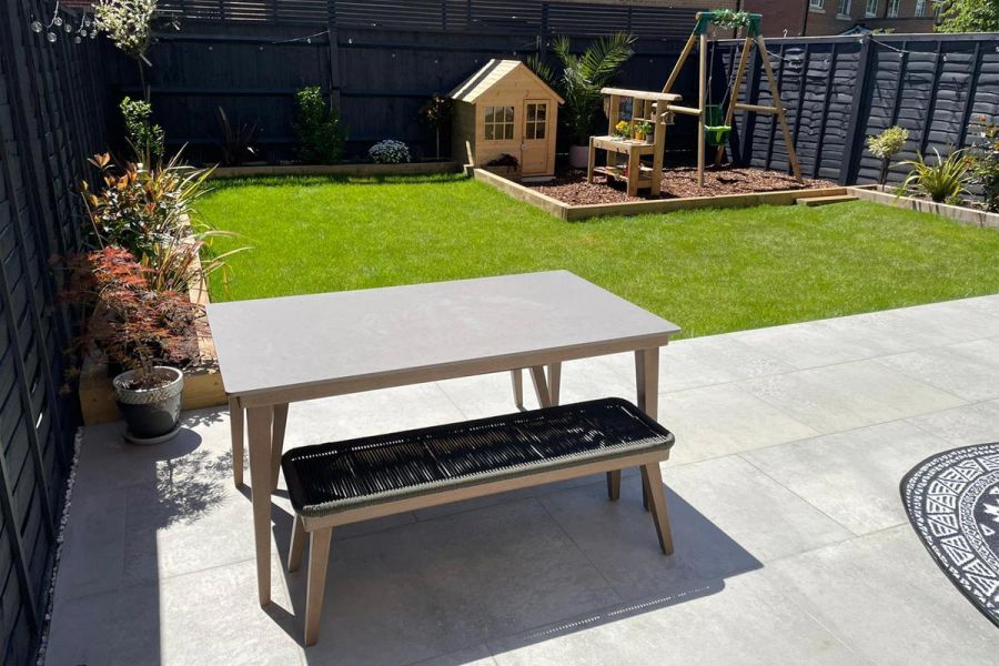 Small family back garden with a Light Grey Porcelain patio, artificial lawn and a raised small childrens play area.