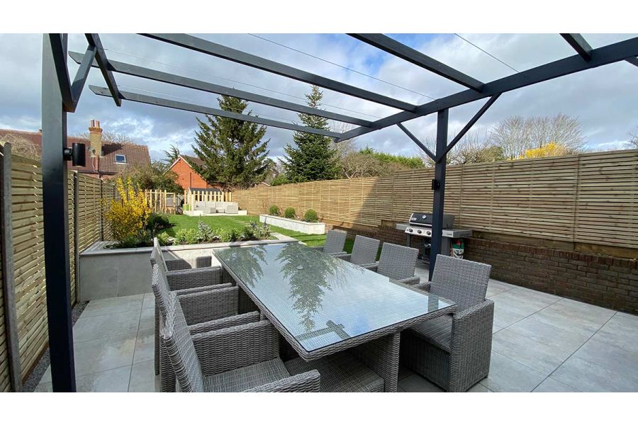 8 seater Rattan dining set on top of a Light Grey Porcelain patio and sat underneath a metal pergola feature.