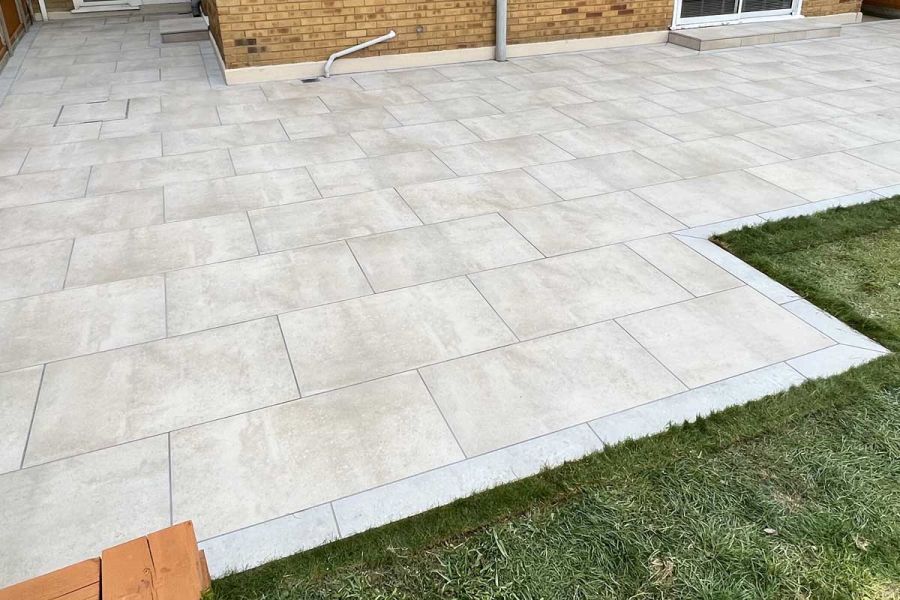 Light Grey Porcelain Plank Paving laid as edging to patio of paving slabs laid running bond. Built by Delta Landscape Solutions.