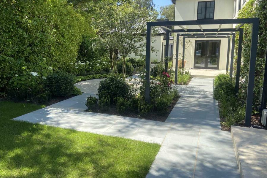 Kota Blue Limestone paving, partly covered with long pergola, divides beds, grass and borders. Design by Thouvenin Landscapes.
