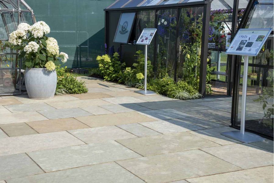 Different sized slabs of Kota Brown limestone paving laid in courses on trade stand , demonstrating greenhouses at flower show.