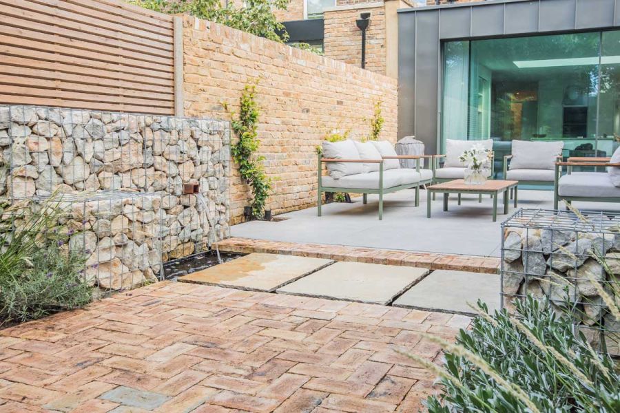A pathway of London Mixture Clay Paver Bricks next to a water feature. Caged rocks are artfully used to create copings.