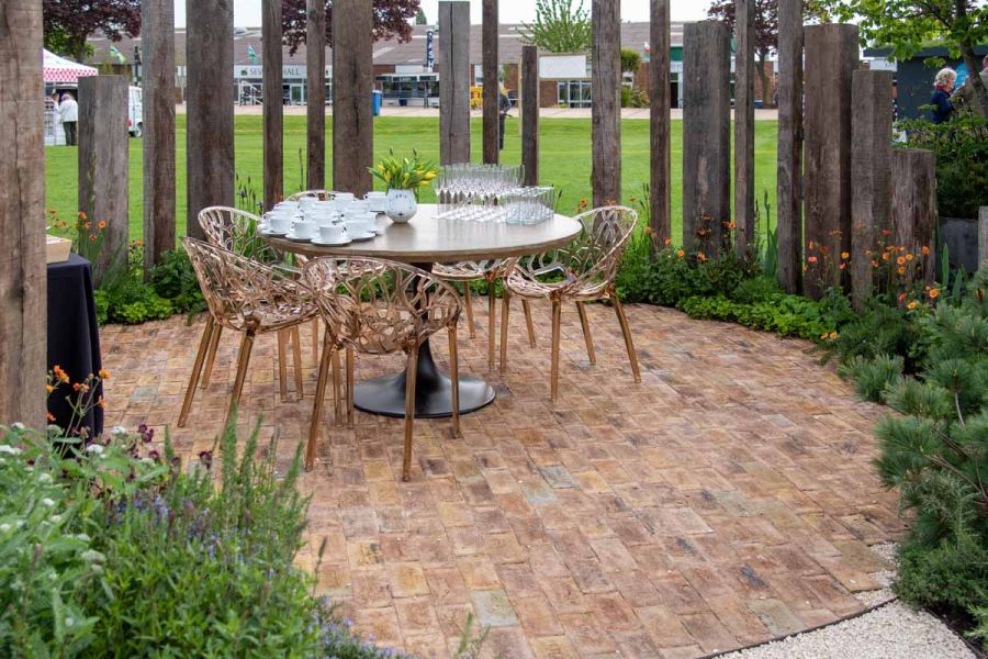 At RHS Malvern, table and chairs on London Mixture Clay Paving circle laid within thin edging, edge bricks cut to curve.