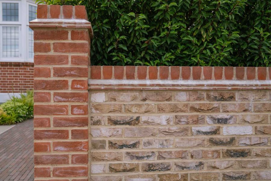 Wall of London Mixture facing bricks, topped with soldier course and abutted by pillar of red brick to match house behind.