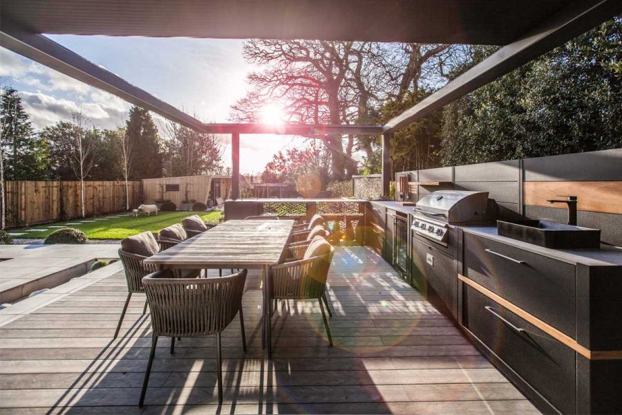 Luna DesignBoard composite decking under metal pergola with outdoor kitchen. Design by Simon Orchard. Built by Graduate Landscapes.
