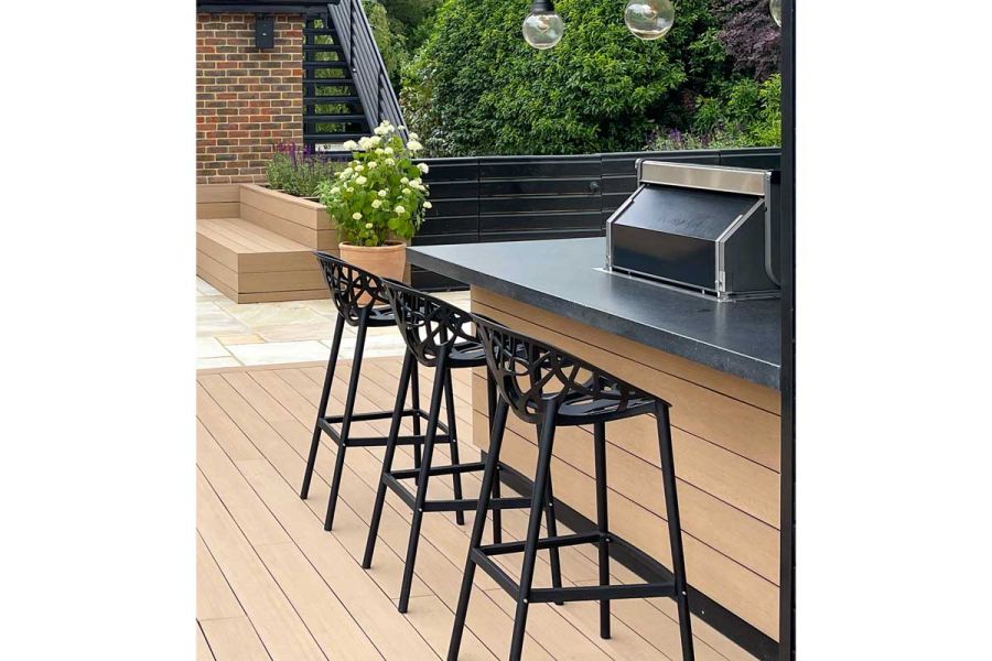 At counter 3 black bar stools sit on Cinnamon DesignBoard composite decking, matching bench in background. Design by Marlene Lento.
